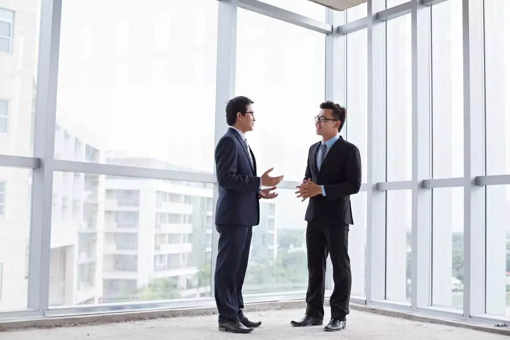 Two men standing in a room discussing real estate referral fees