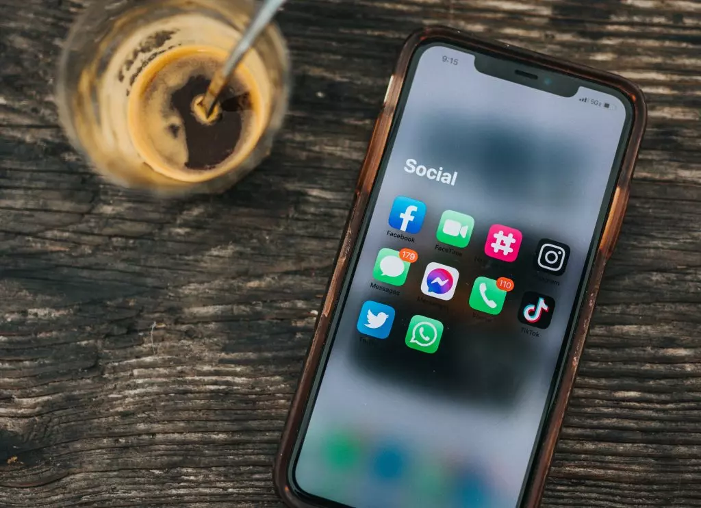 A smartphone with social media apps on a table next to a cup of coffee