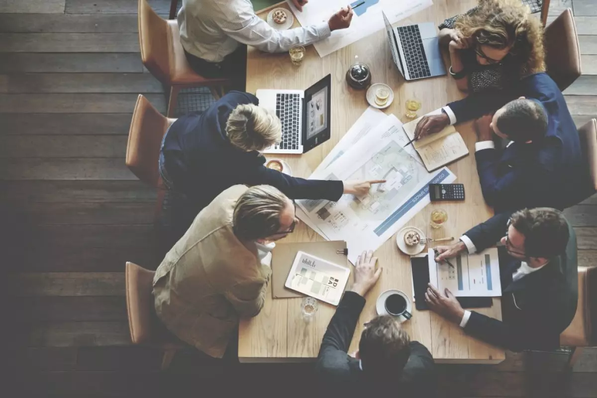 A group of business people sitting around a table. The truth about being a real estate agent is that it requires team building