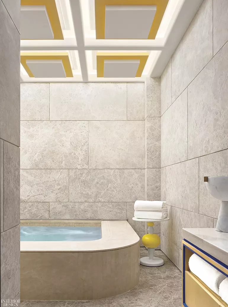 This modern bath features a curved rub with cement walls and golden accents