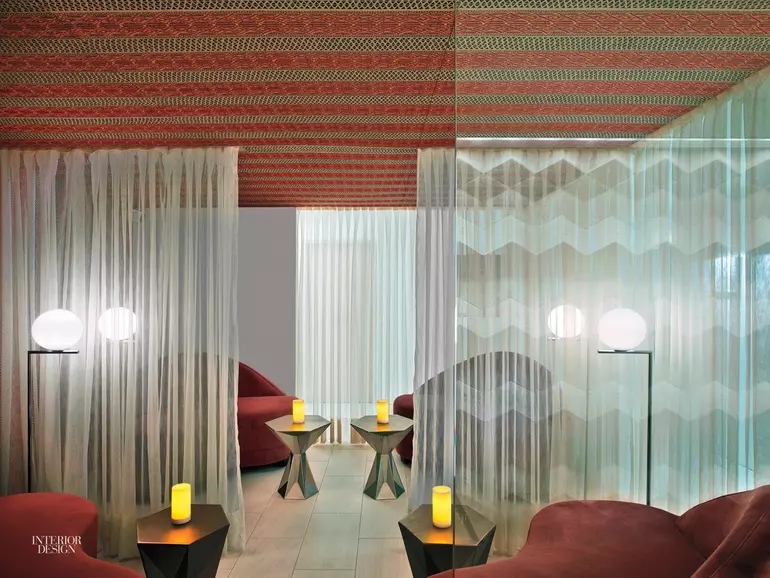 Wooden slats line this massage room with a white massage bed at the center and flowing candles