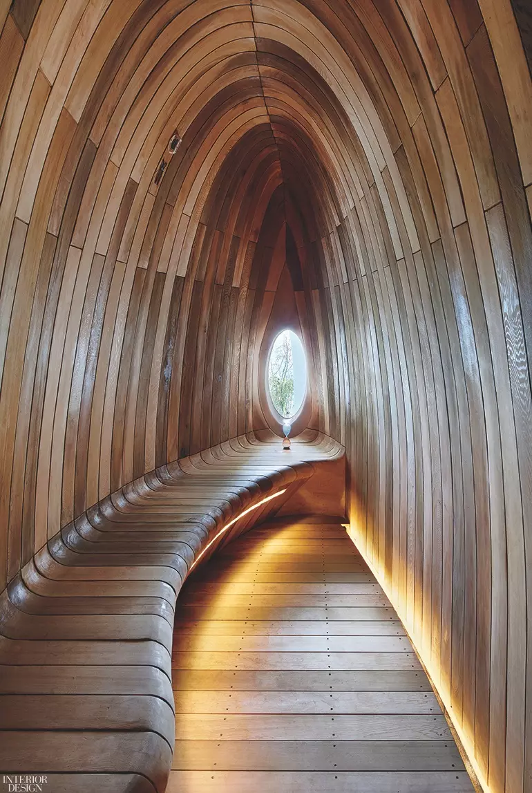 A wooden archway leads to a small oval window at one end offering a curved bench for seating