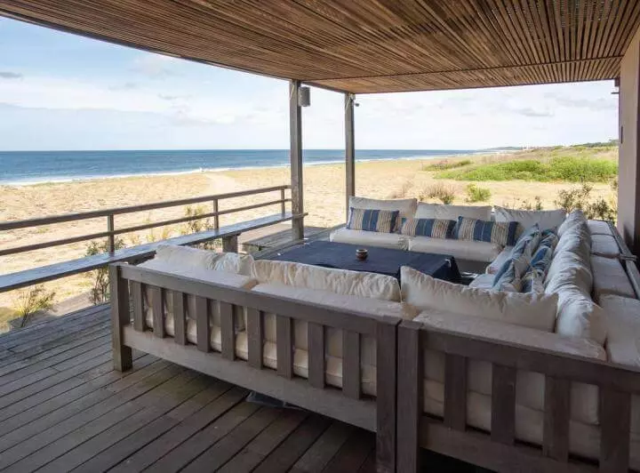 The oceanfront terrace glass railing allows the view to reach the blue horizon. Glass, iron, and wood contribute to low maintenance and adaptability to the environment.