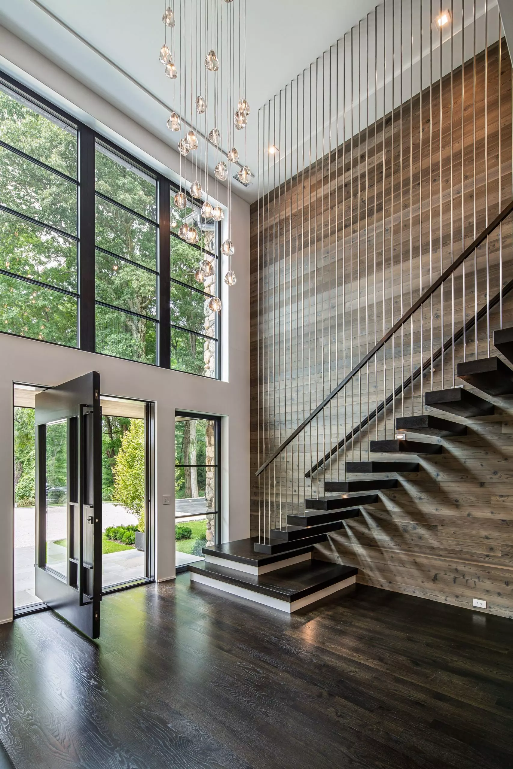 Modern home with a floating staircase built into the wall with tread to ceiling metal balusters.