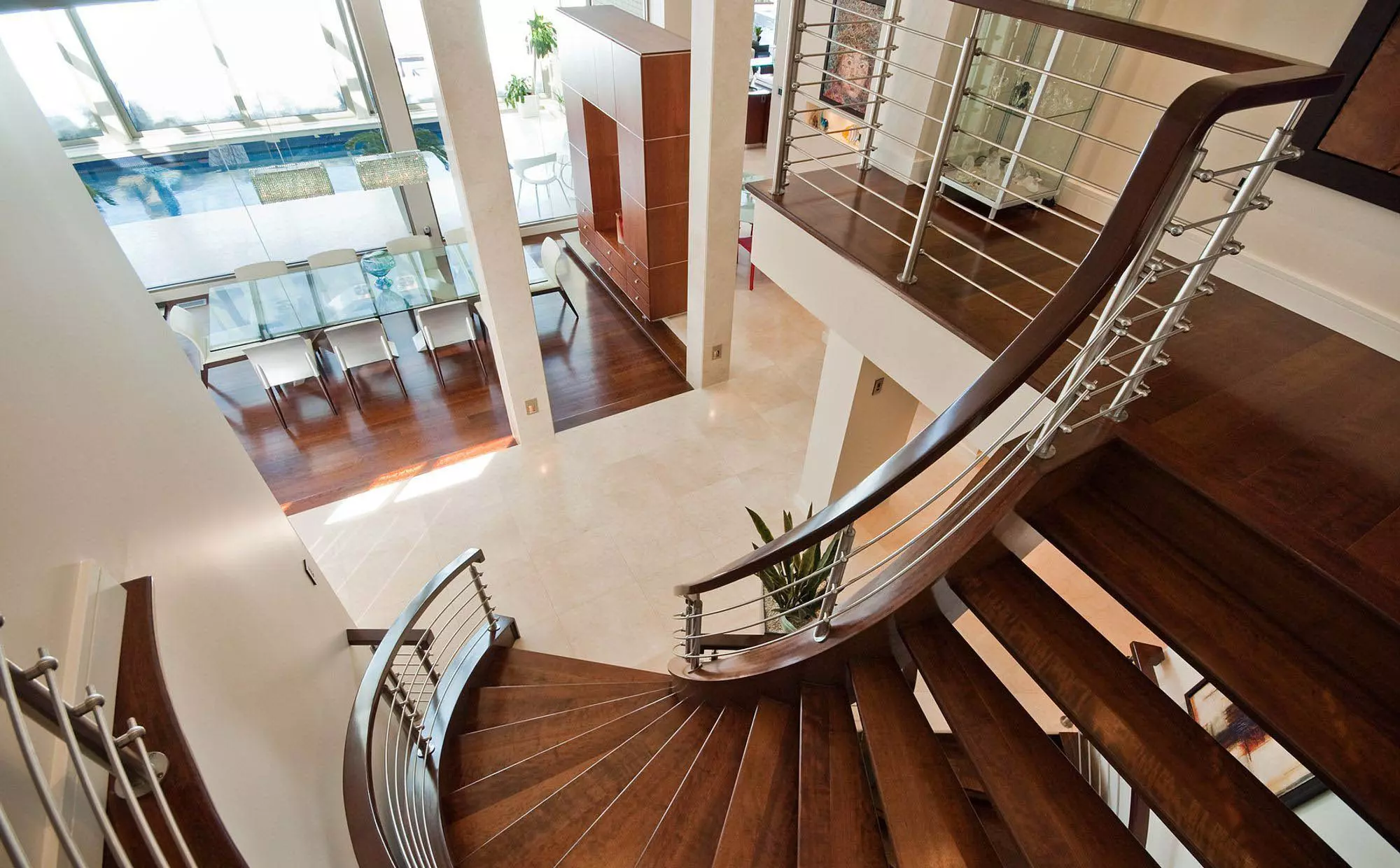 Beautiful curved wood modern staircase design with metal balusters and wood handrail. Matching hardwood floors. Dark brown stain with a light sheen.