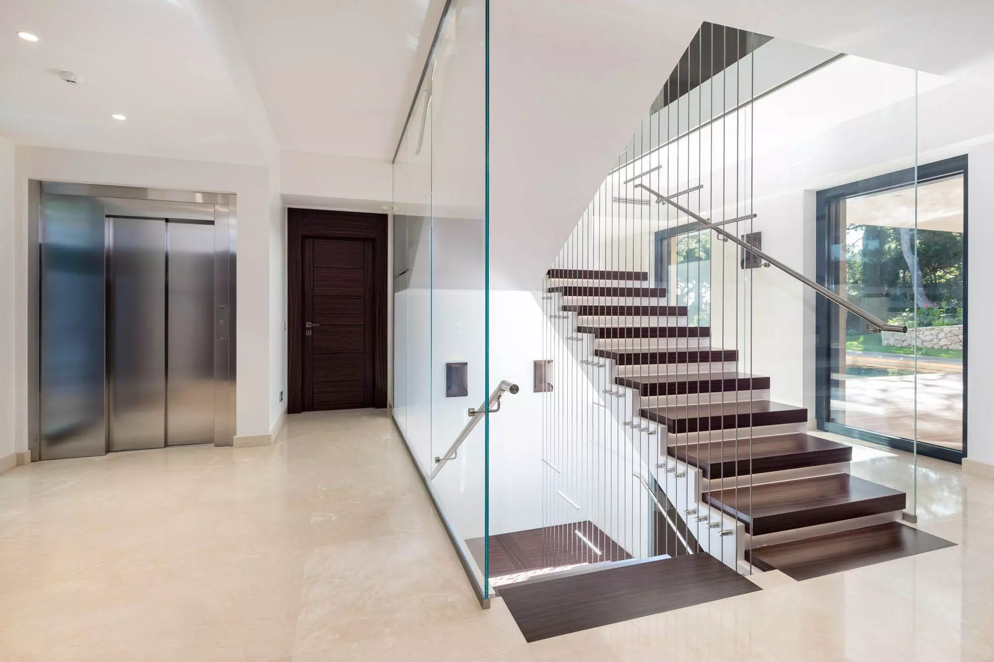 Modern wood, wire, and glass wall staircase. Dark wood steps with white risers. Glass and wire sidewalls.