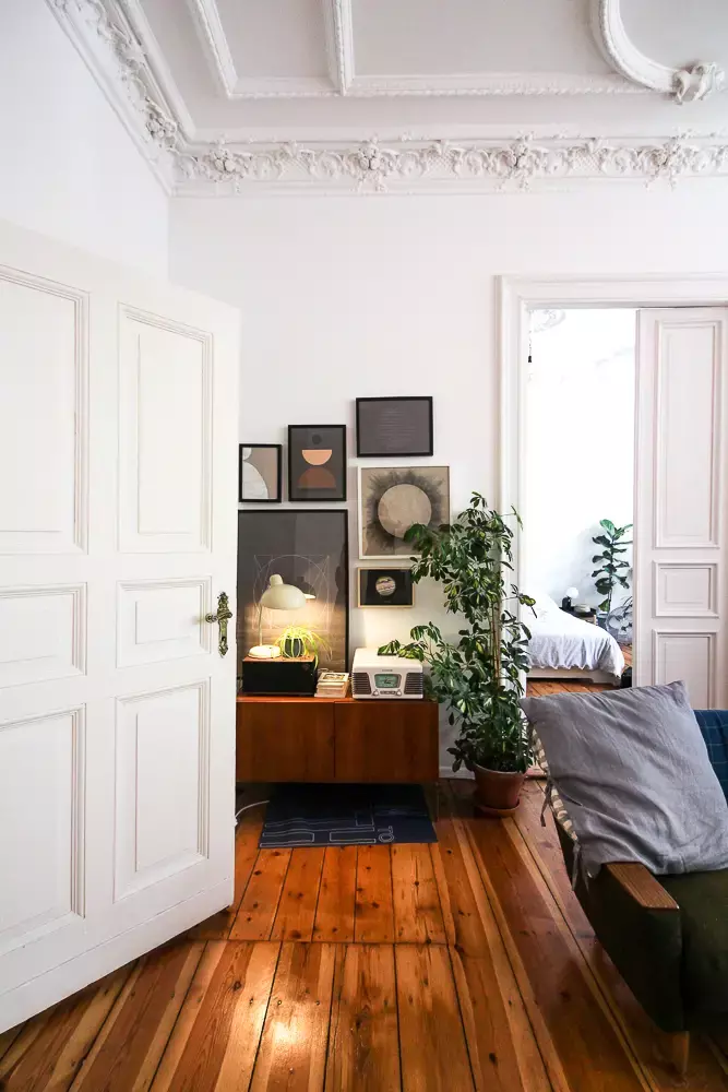 A room with detailed ornate moulding, a couch, and a sideboard. Portrays a neoclassical interior design style.