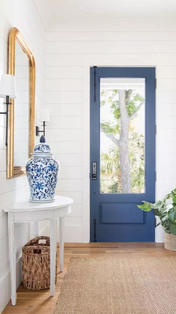 Shiplap walls, a natural fiber rug, and a glorious blue door create the quintessential coastal entryway