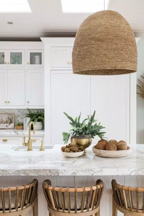 Love this beautiful modern coastal kitchen design with a woven pendant light, white cabinets, and modern counter stools