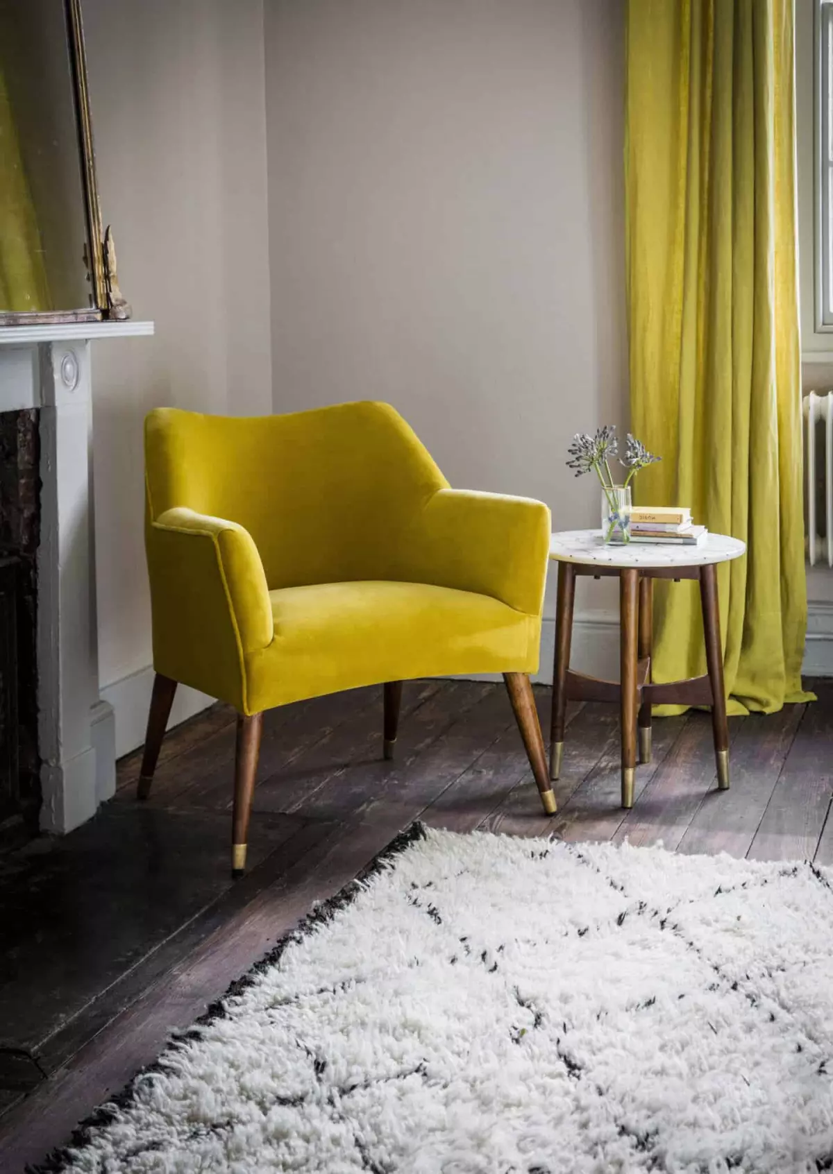 Pantone Colour of the Year 2021 - Illuminating. The colour psychology behind using yellow in interiors. A velvet yellow chair from Atkin & Thyme in the corner of a living room with a side table beside it and yellow curtains behind