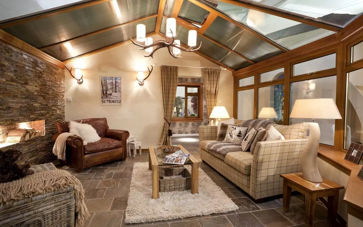 Open layout first floor of the house with exposed lacquered ceiling beams and pastel-colored interior with a stone-clad fireplace