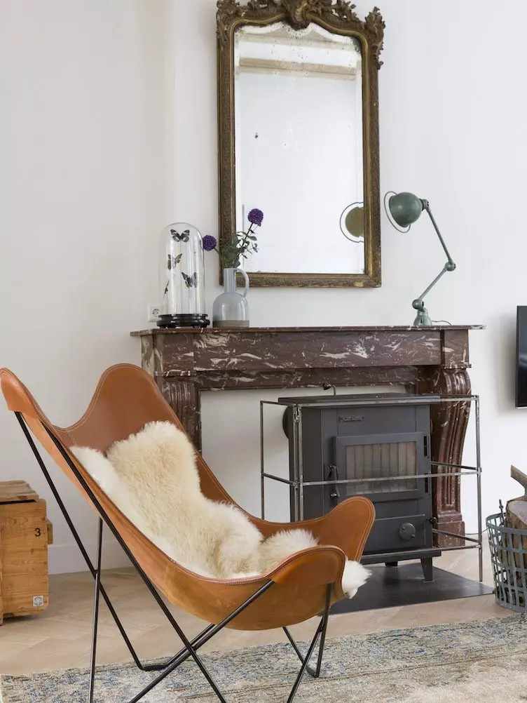 Contemporary living room with large windows, a butterfly chair, and neutral colors.