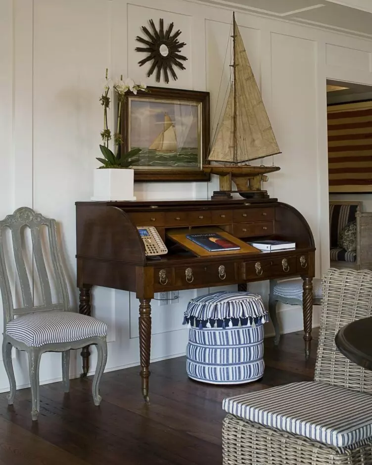 Traditional wood roll top desk with wicker accent chair and blue and white striped ottoman