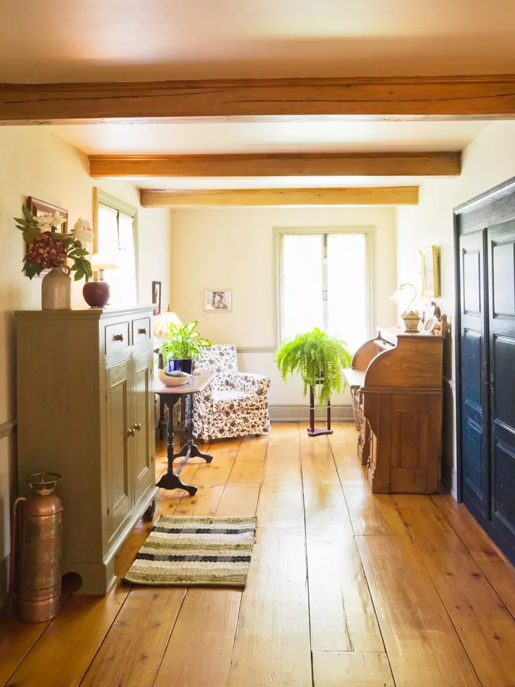 Hallway with wood roll top desk with floral armchair and wood sideboard