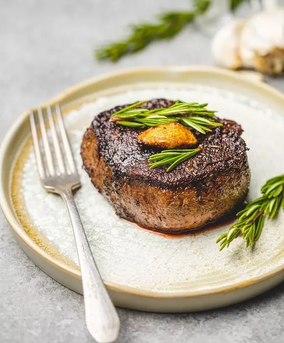 An alcoholic drink with ice and rosemary in a glass tumbler used as a food photography prop