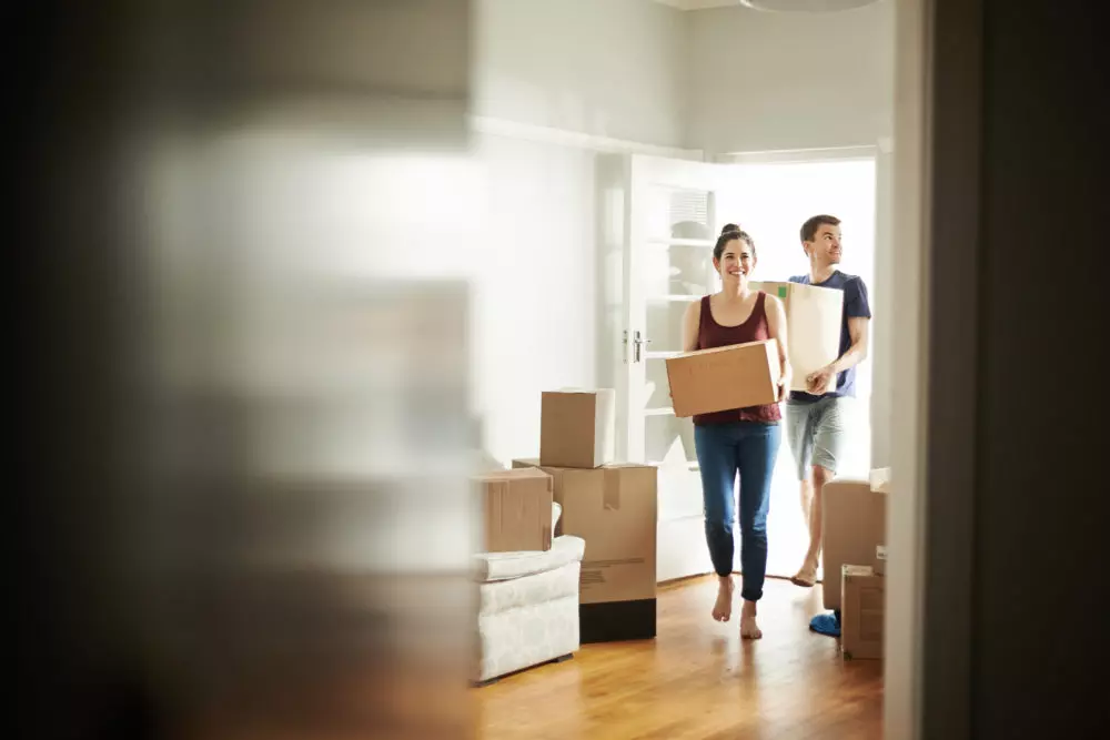 Shot of a young couple carrying boxes into their new place.