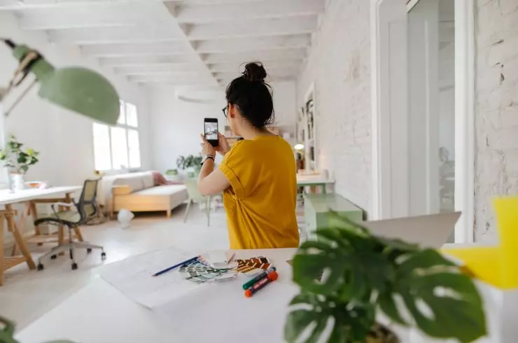 A woman taking photos of a living room under the natural light