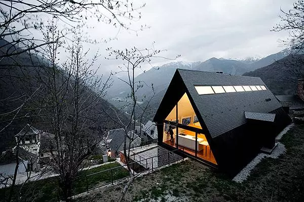 Triangular house design with large windows and beautiful brook view