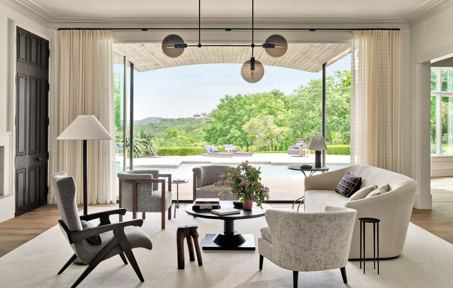 light-filled living room with seating and sofas overlooking a pool in home by designer Chad Dorsey