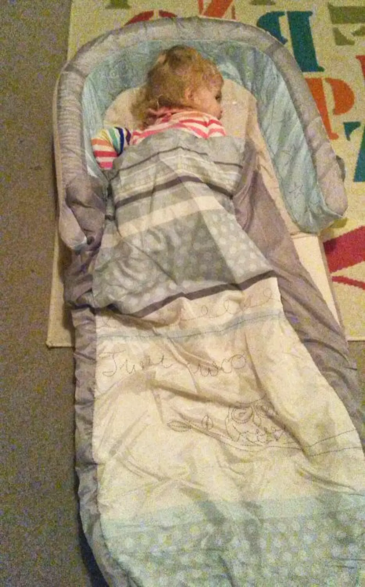 Toddler curled up in a Ready Bed inflatable travel bed