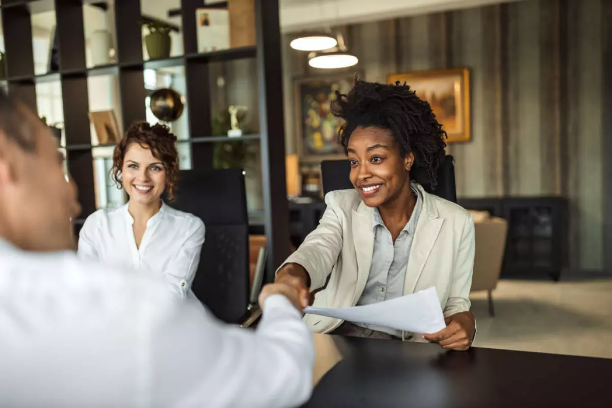 Two people are shaking hands over a real estate transaction